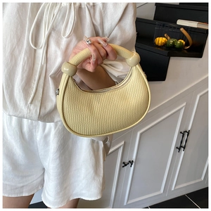 Detail of cream pleated crescent bag featuring large bead handle and metallic zipper