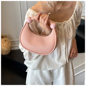 Pink crescent handbag detail with vertical texture and large decorative round beads
