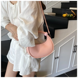 Detailed texture of pink pleated crescent bag with spherical top handle and slim strap