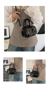 Detail of black glossy patent leather mini square bag with silver metal buckles and handles