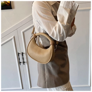 Detail of beige pleated crescent bag with spherical accents and detachable strap