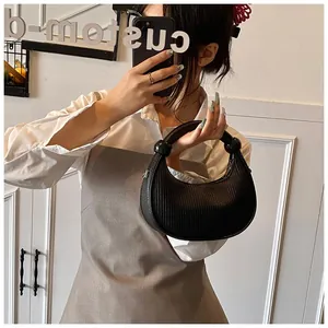 Detail view of a black pleated crescent handbag with knotted ball accents on the handle