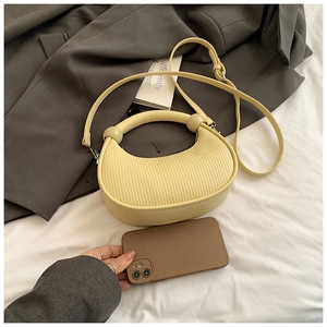 Detailed view of yellow half-moon bag with vertical pleated texture and round handle
