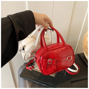 Detail of red and cream glossy mini square bags with bow buckles and metal hardware