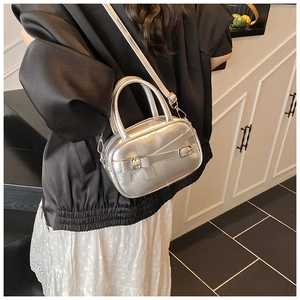 Silver metallic crossbody bag with bow buckle detail shown on model for fashion styling