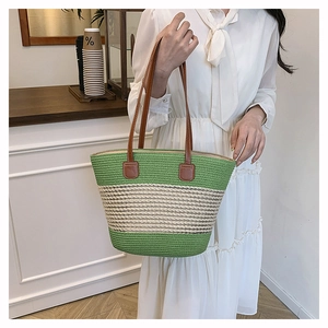 Close-up of green striped woven tote showing leather strap detail and sturdy stitching