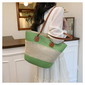 Detail of green striped straw tote bag with brown leather handles and large capacity