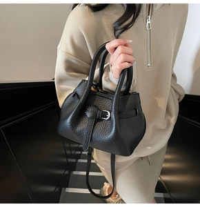 Detail of black lychee grain leather handbag with silver buckle and adjustable strap