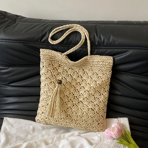 Chic woven shoulder bag featuring scalloped hollow patterns and bohemian beaded tassels