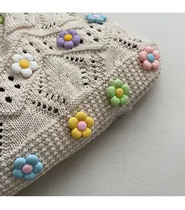 Détail du sac tricoté crème avec fleurs 3D colorées et motif de tissage évidé