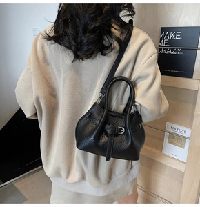 Close-up of black lychee leather handbag showing texture and stylish buckle strap detail