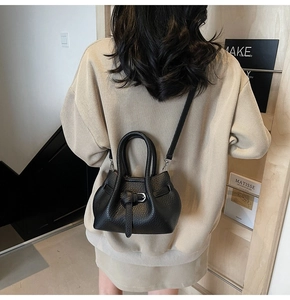 Rear view of a model wearing the black pebble leather crossbody bag with beige knitwear