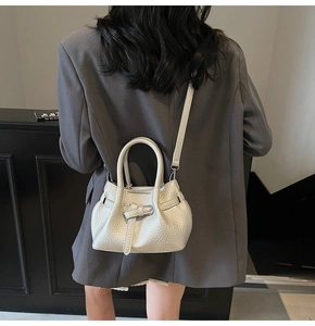 Detail of silver lychee texture leather mini crossbody bag with buckle held by model