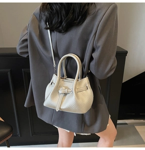 Detailed macro view of the silver leather bag's pebble grain texture and decorative buckle