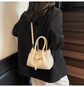 Detailed texture of off-white lychee pattern leather shoulder bag on a female model