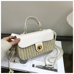 Detail of woven straw handbag featuring white leather flap and gold ring handle