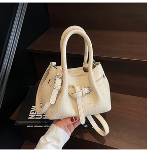 Detailed shot of cream lychee grain leather handbag with knot strap and silver buckle