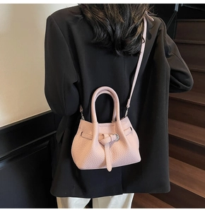 Detail of pink lychee leather bucket bag with metal buckle and shoulder strap