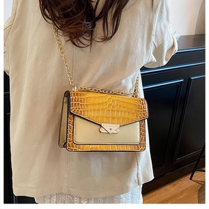 Dettaglio della trama a coccodrillo e tracolla a catena su borsa a tracolla alla moda