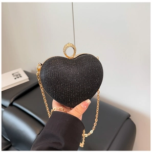 Détail d'un sac de soirée en forme de cœur avec paillettes noires et chaîne dorée