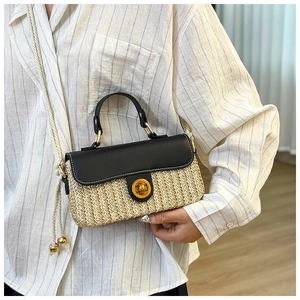 Detail of summer straw handbag with black leather flap and golden twist lock closure