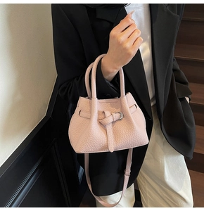Detail of pink lychee grain leather handbag with silver metal buckle and top handles
