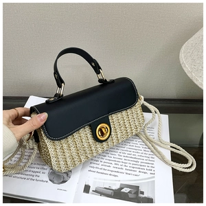 Detailed view of woven straw handbag featuring black leather flap and golden twist lock