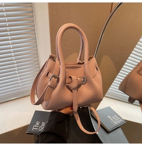 Detail of light pink pebbled leather handbag with silver hardware and decorative buckle
