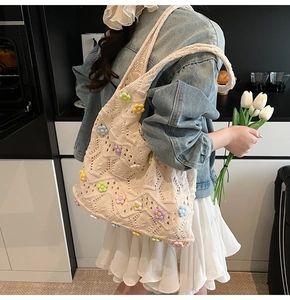 Détail du sac cabas au crochet avec des fleurs 3D tricotées colorées sur tissu beige