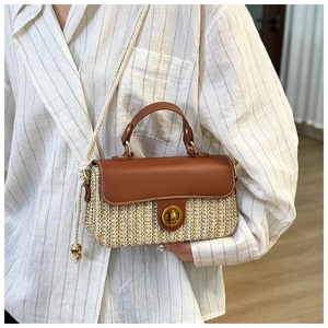 Detail of woven straw handbag with brown leather flap and vintage metal twist lock clasp