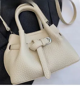 Detail of cream white lychee texture bucket bag with adjustable strap and top handle