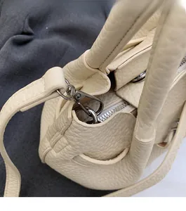 Macro detail of creamy leather handbag showing silver zippers and high-quality hardware
