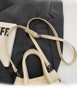 Detail of adjustable leather shoulder strap with silver buckle on beige textured handbag
