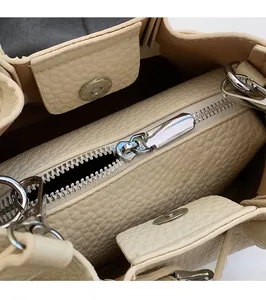 Detail of lychee pattern leather bag showing silver zipper and magnetic buckle closure