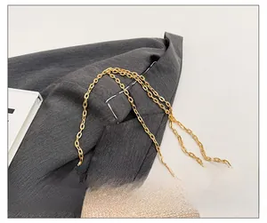 Détail de la bandoulière en chaîne dorée sur un sac de soirée à texture perlée