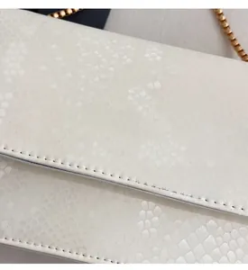 Detailed macro view of white snake embossed leather and golden Fashion lettering on the bag