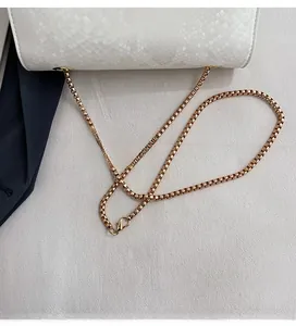 Close-up of white crocodile texture leather bag with elegant gold chain and square clasp