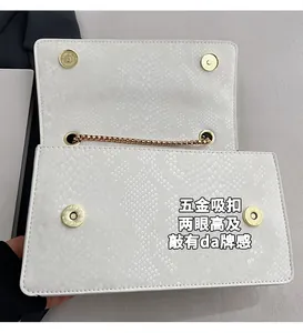 Detail of white snakeskin texture flap bag featuring a gold magnetic clasp and chain