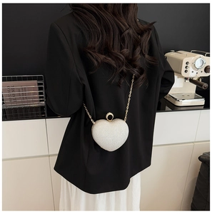 Détail du sac de soirée cœur pailleté avec bandoulière chaîne sur une tenue de mannequin