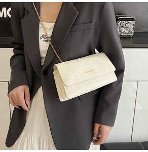 Detail view of off-white faux snake texture bag with gold chain and fashion lettering