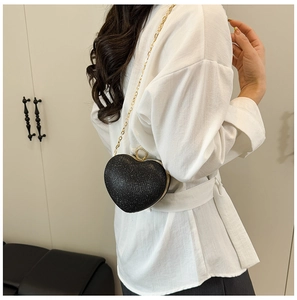 Détail d'un sac de soirée noir pailleté en forme de cœur avec fermoir doré et chaîne