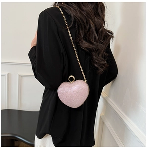 Mannequin portant un sac de soirée cœur rose scintillant avec anneau doré et chaîne