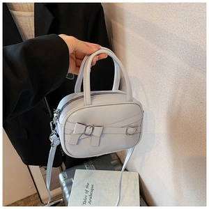 Light blue mini handbag with bow detail and silver buckle shown in a lifestyle setting