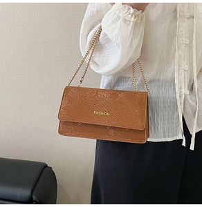 Close-up of brown snakeskin print handbag with gold chain strap and Fashion logo