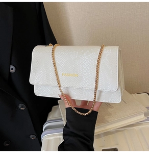 Detail view of a white snake-patterned crossbody bag with a golden chain strap and logo