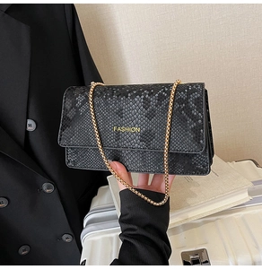 Detail of black snake pattern faux leather texture with gold Fashion text on crossbody bag