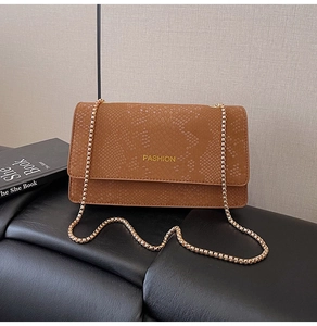 Detail of brown snakeskin texture flap bag with gold Fashion lettering and chain strap
