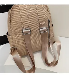 Detail of beige woven backpack featuring adjustable wide straps and side zipper pocket