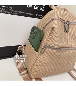 Detail view of the beige backpack side pocket showing convenient storage for a phone