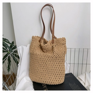 Macro detail of handmade woven straw tote bag with floral patterns and brown leather handles